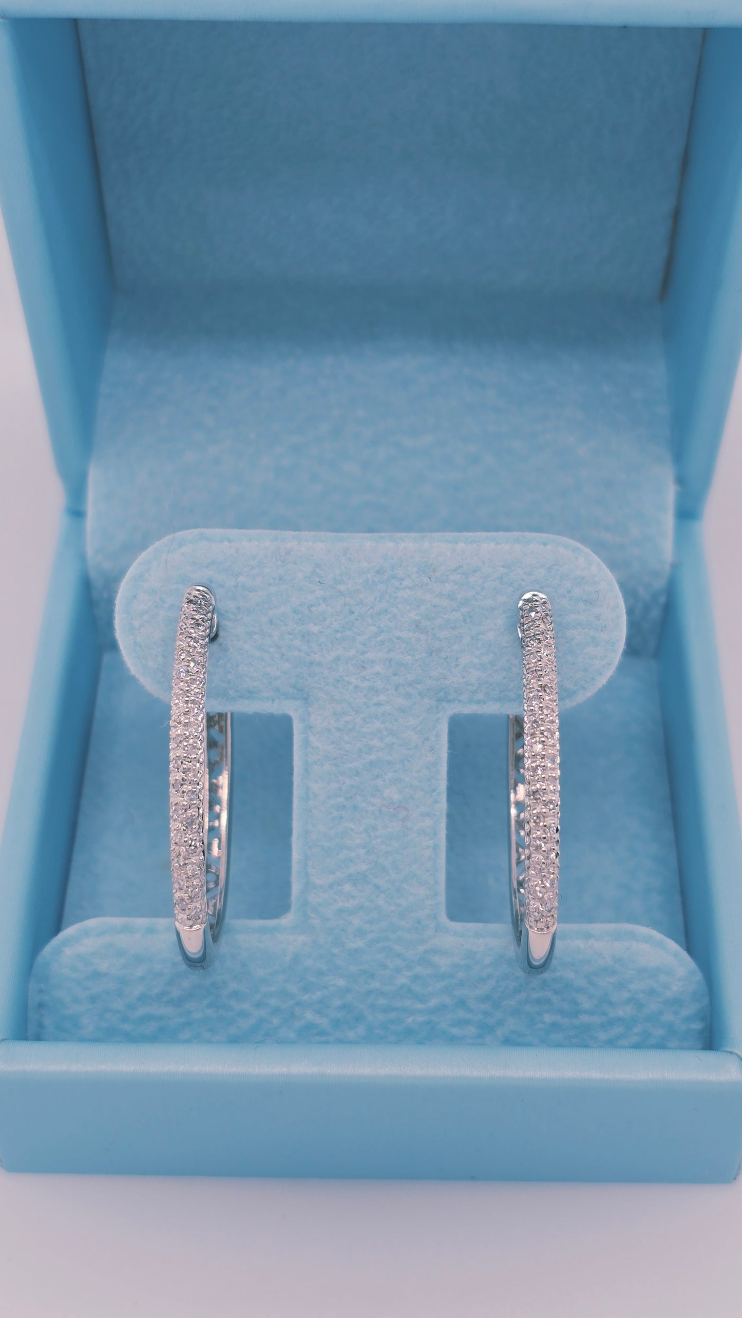 14k white gold oval hoop earrings with two rows of pave-set natural diamonds on the front, measuring 1.15" x 0.75", total diamond weight 0.60 carat, elegant and modern design.
