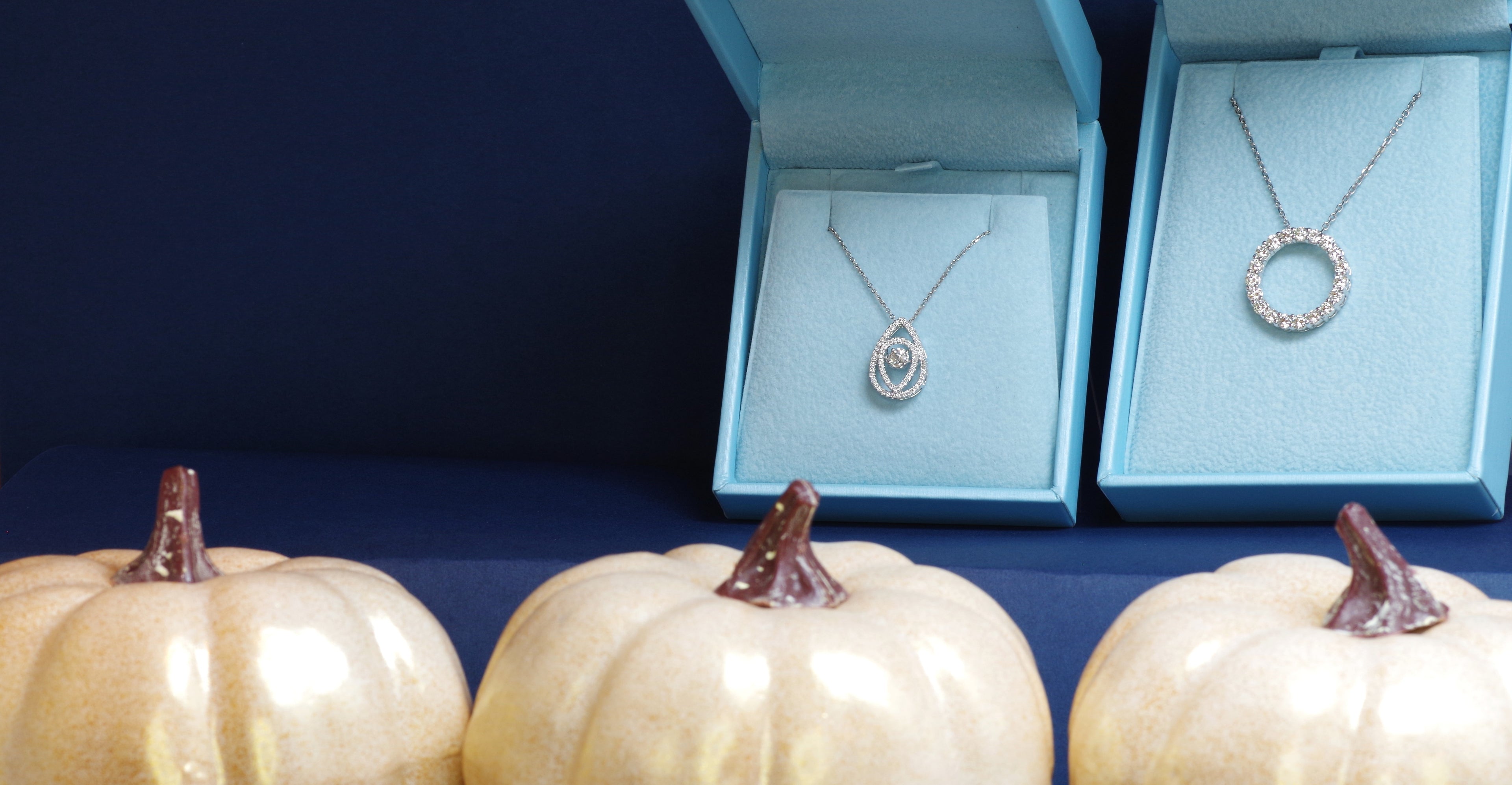 Diamond necklaces in jewelry boxes on a blue background with pumpkins.