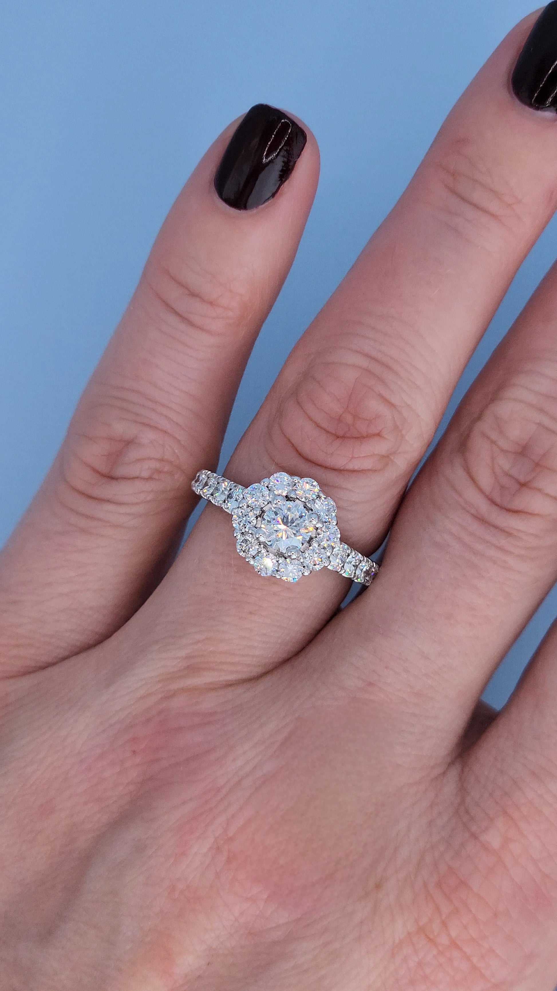 White gold promise ring with diamonds on a finger against a blue background