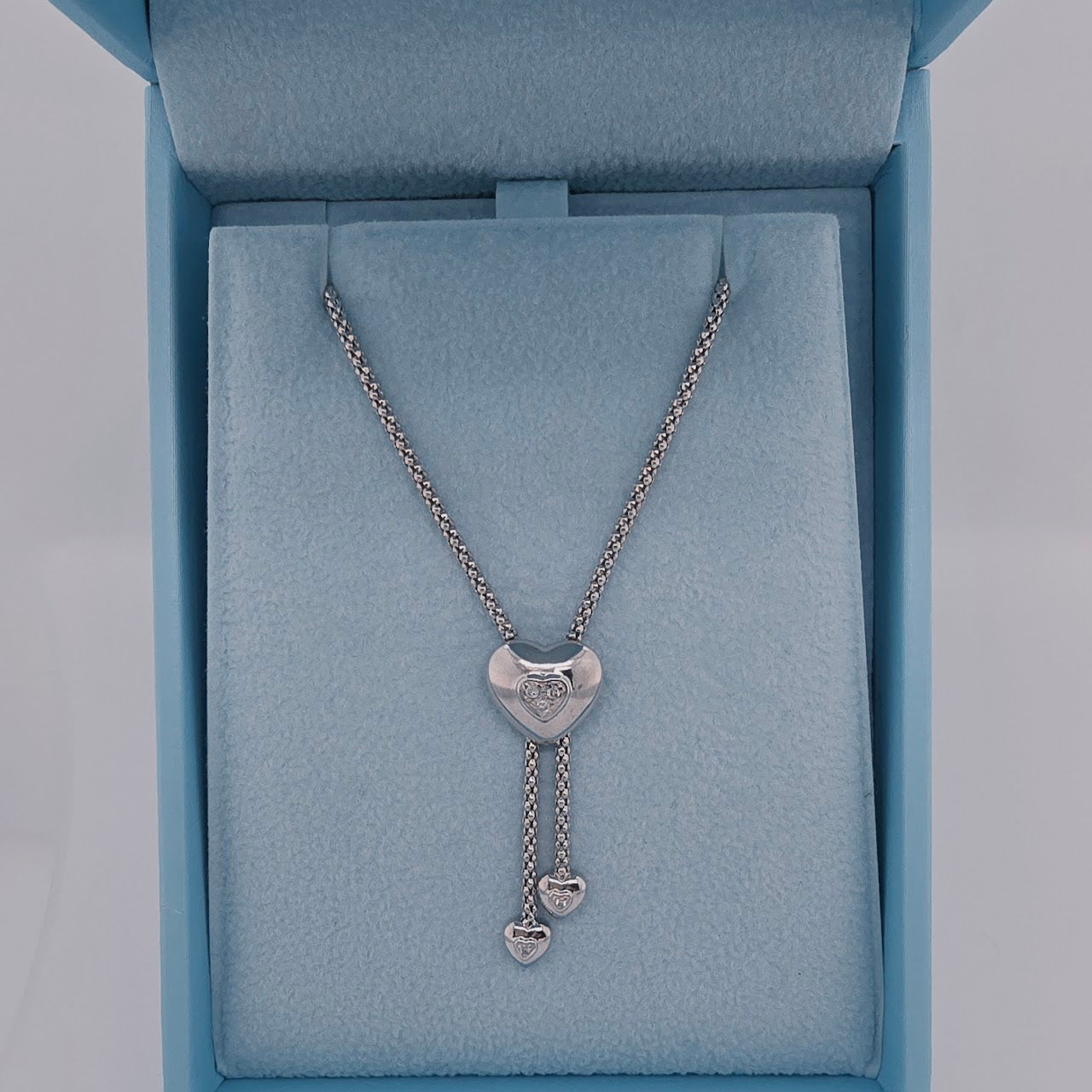 white gold necklace with heart pendants in a blue jewelry box
