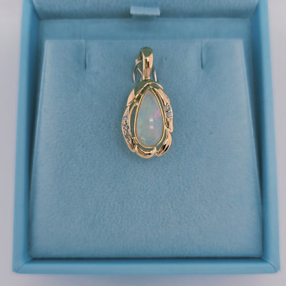 14k yellow gold pendant with a pear-shaped cabochon opal and round diamond accents, designed with a freeform setting and hinged bail for omega chains.